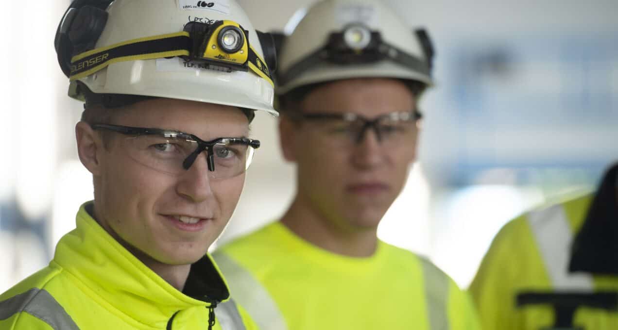 To OneCo-ansatte ser på kameraet, iført hjelmer og briller.