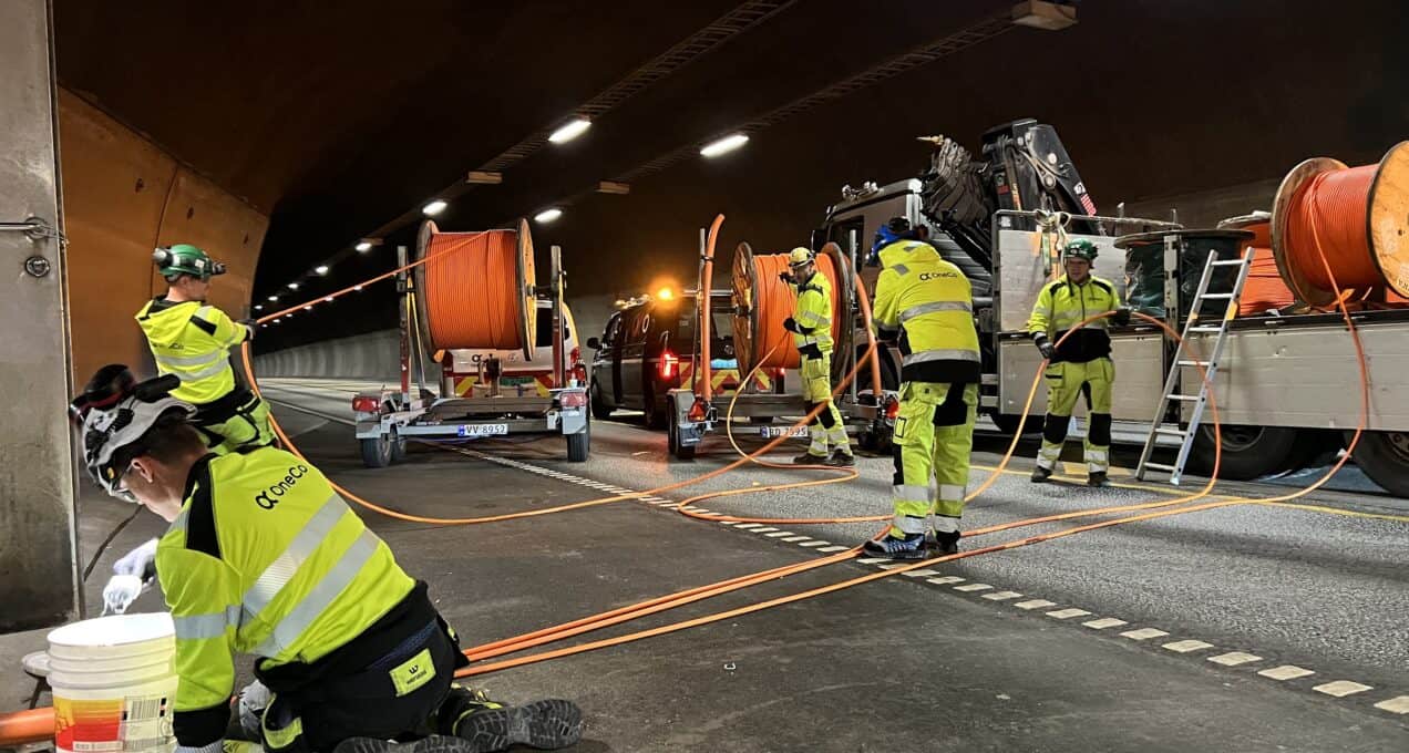 A team of five workers is seen unravelling large cables for installation in a tunnel.