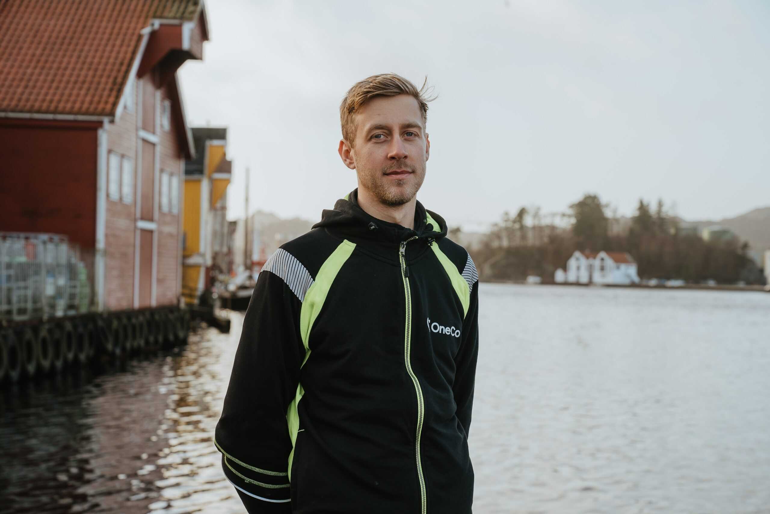 A OneCo worker is seen looking directly into the camera. The ocean is visible in the background.