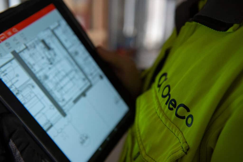 A closeup of a OneCo worker looking at an ipad. A technical drawing is visible on the screen.