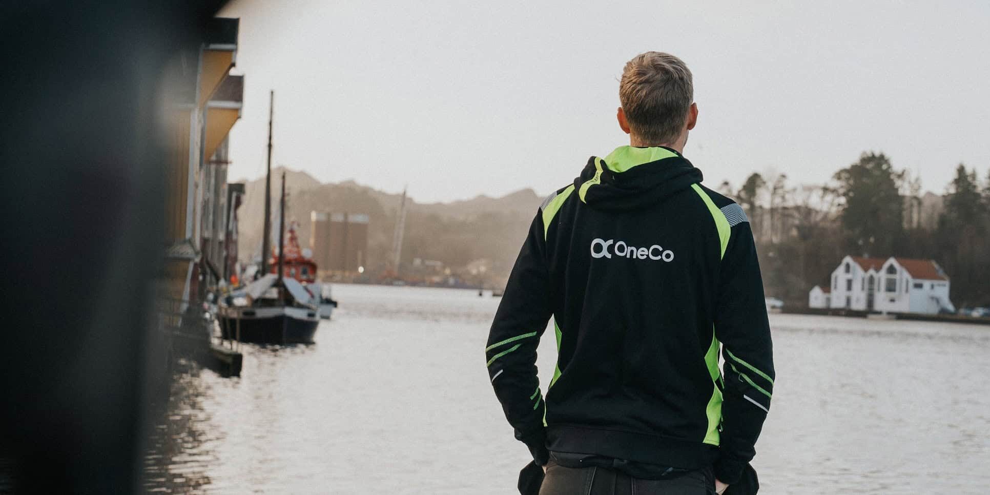 OneCo worker seen looking out over the ocean with houses and boats in the distance.